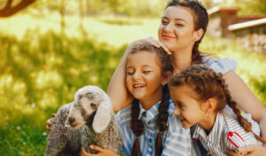 Mujer y niñas felices con oveja en entorno rural, turismo familiar en Albergue La Casa de Gandara.