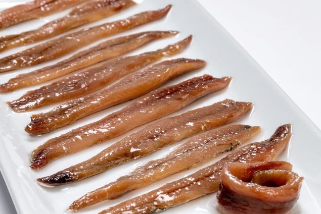 Filetes de anchoa en plato blanco, destacando la calidad y frescura del producto.