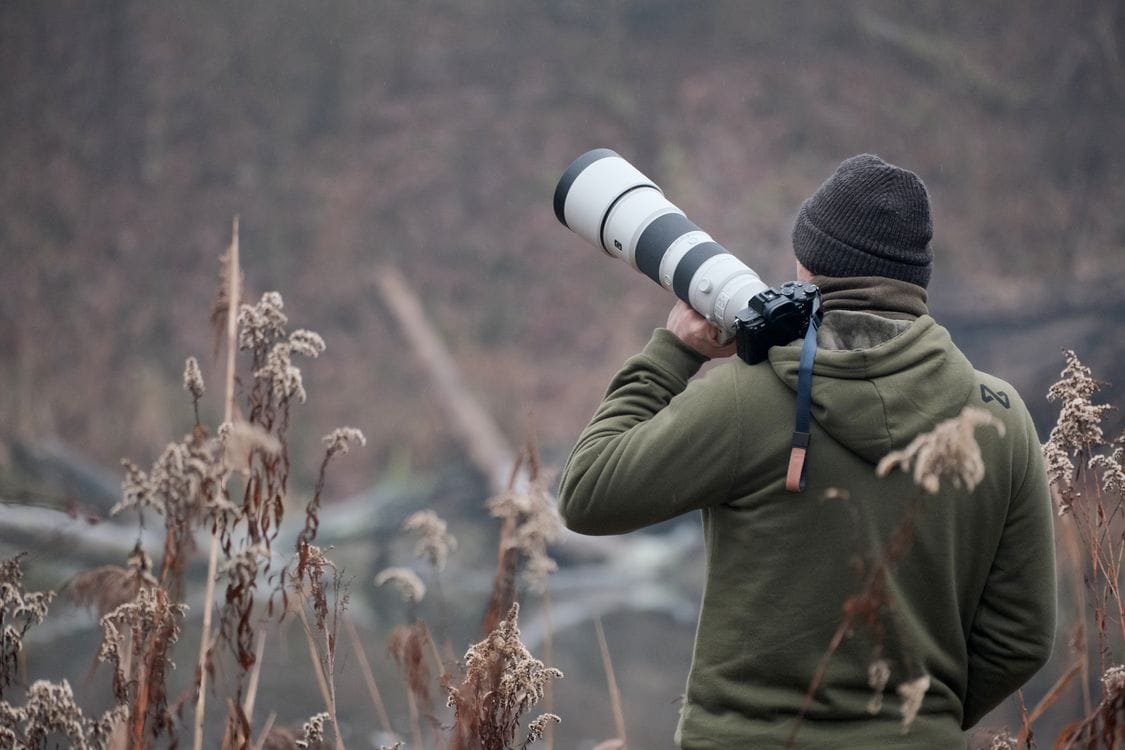 Fotógrafo con teleobjetivo en la naturaleza - equipamiento fotográfico profesional fauna