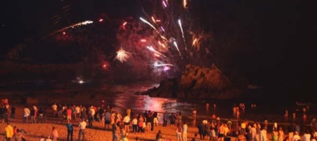 Fiesta en la playa con fuegos artificiales y multitud de visitantes disfrutando de la noche en Gandara. Cantabria nocturna descubre la vida nocturna en el campo